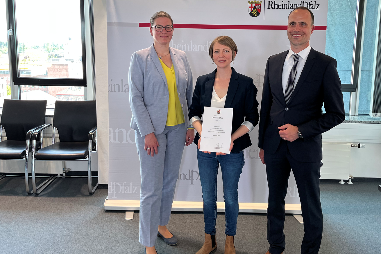 Prof. Dr. Constanze Juchem-Grundmann und Minister Clemens Hoch gratulieren Lena Friedrich (Mitte) zur Auszeichnung ihrer exzellenten Lehre. Die zweite Preisträgerin der Universität, Annika Feyen, konnte nicht an der Verleihung teilnehmen. Bild: MWG
