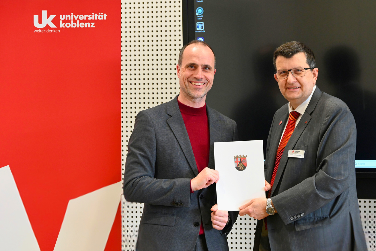 Wissenschaftsminister Clemens Hoch und Universitätspräsident Prof. Dr. Stefan Wehner mit dem übergebenen Zuweisungsschreiben. Bild: Universität Koblenz / Sebastian Heinz