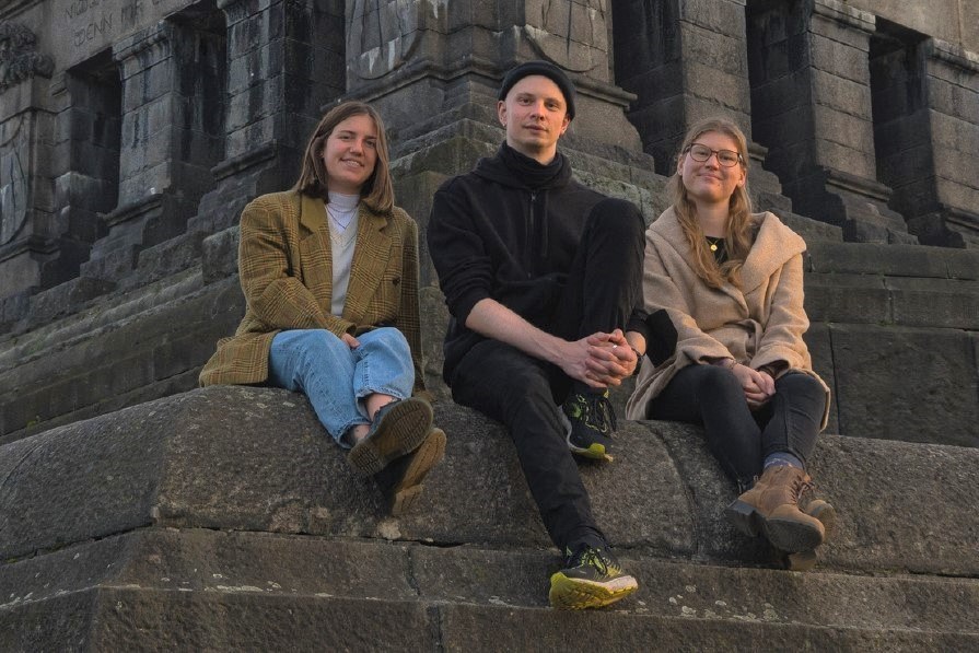 Die Studierenden (v. l. n. r.) Lotta Pies, Jan-Lucas Klein und Sarah Weißenfels, hier am Deutschen Eck in Koblenz, konzipierten mit ihren Kommilitoninnen Sandra Keul, Karolin Roth und Rokiya Kemin den Audio Walk. Bild: UKL / Jan-Lucas Klein