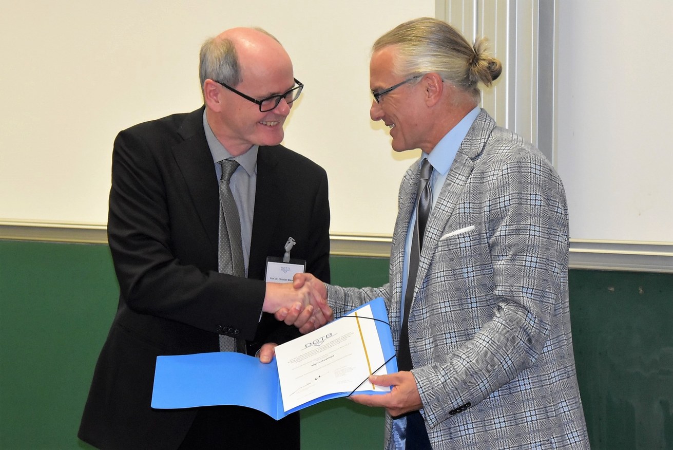 Der Erste Vorsitzende der DGTB, Prof. Dr. Christian Wiesmüller von der Pädagogisches Hochschule Karlsruhe (links), übergibt die Urkunde an den wissenschaftlichen Leiter der technikcamps, Dr. Martin Fislake von der Universität in Koblenz. Bild: DGTB