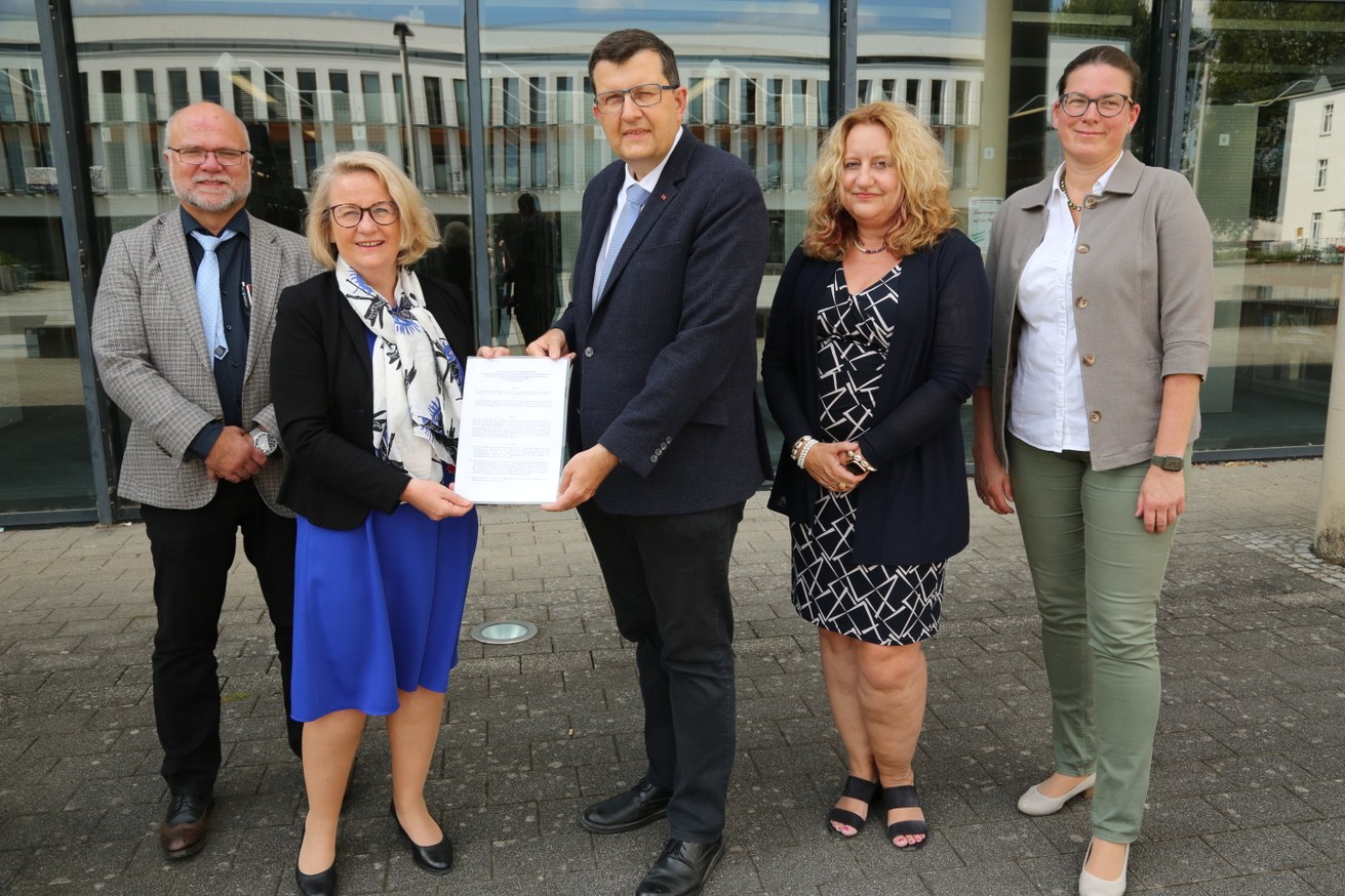 Tobias Heilig und Prof. Dr. Julia Sander von der VPU sowie Prof. Dr. Stefan Wehner, Prof. Dr. Claudia Quiaser-Pohl und Prof. Dr. Constanze Juchem-Grundmann von der Universität in Koblenz mit dem Vertrag vor der Universitätsbibliothek Koblenz. Bild: UKL